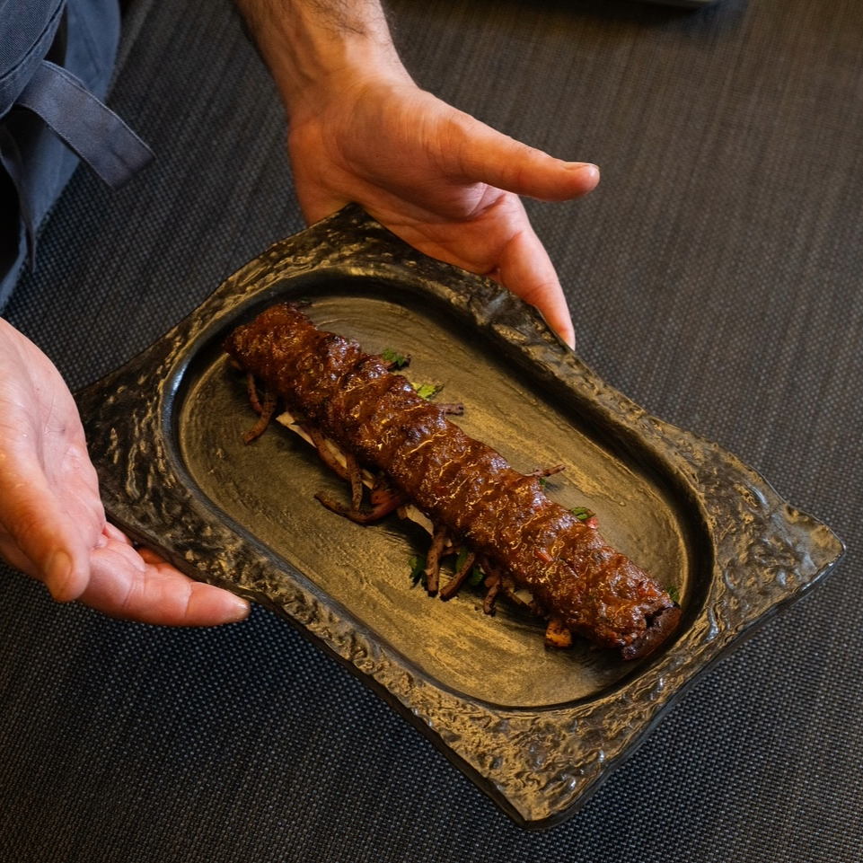 Chef Okay Inak serving Garlic Kebab on the Chiseled Serving Platter during service at his restaurant Sora Craft Kitchen